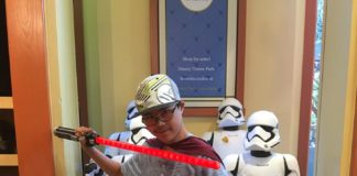 Tanner holding Star Wars swords at Disneyland store.